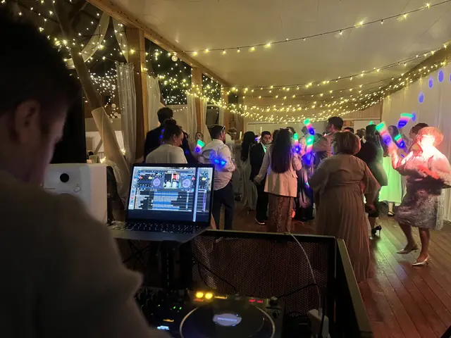 Sebastian vid DJ-bordet medan gästerna dansar på ett bröllop på Lane Loge i Uddevalla