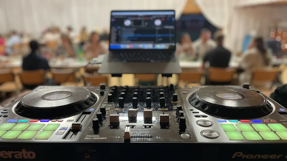 DJ-bås med mixer och laptop under en fest